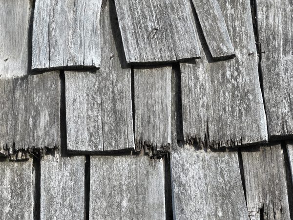 Close-up of weathered cedar shakes with splits and worn edges